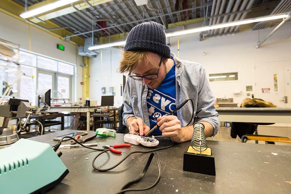 Student soldering electronics as part of tuition free program at University of Rochester